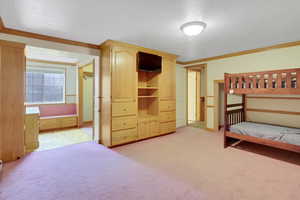 Bedroom featuring a textured ceiling, crown molding, and light carpet