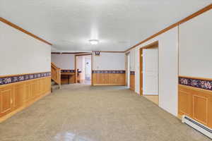 Interior space with ornamental molding, a textured ceiling, and a baseboard heating unit