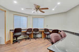 Office area with built in desk, hardwood / wood-style flooring, and ceiling fan