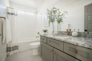 Full bathroom featuring toilet, shower / bath combination with curtain, vanity, and tile patterned floors