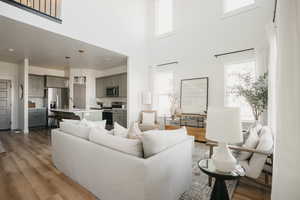 Living room featuring sink, a towering ceiling, and hardwood / wood-style flooring