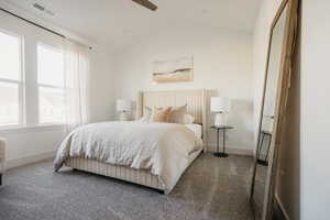 Bedroom with dark colored carpet, multiple windows, lofted ceiling, and ceiling fan