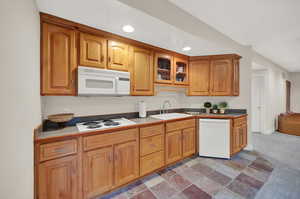 Kitchen with light carpet, white appliances, and sink