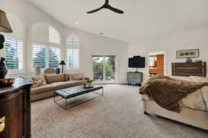 Living room with light colored carpet, ceiling fan, and lofted ceiling