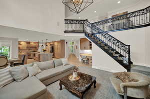 Living room featuring a chandelier, a high ceiling, light hardwood / wood-style flooring, and crown molding