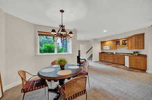 Dining room with light carpet, a notable chandelier, and sink