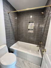 Bathroom with toilet and tiled shower / bath