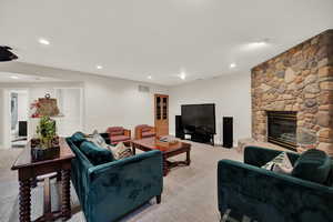 Living room with a stone fireplace and light carpet