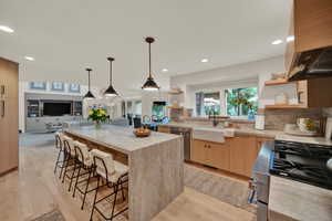 Kitchen featuring a kitchen bar, light wood-type flooring, stainless steel appliances, sink, and a center island