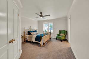 Carpeted bedroom with ceiling fan and crown molding