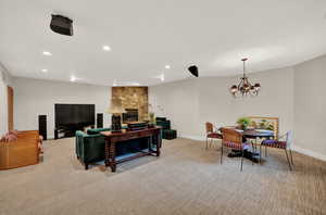 Living room featuring light carpet, a stone fireplace, and a notable chandelier