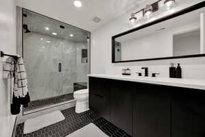 Bathroom with tile patterned floors, vanity, a shower with shower door, and toilet