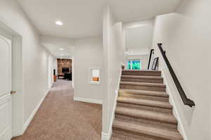 Staircase featuring carpet flooring and a fireplace