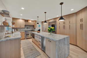 Kitchen featuring built in appliances, light brown cabinets, a spacious island, and light hardwood / wood-style floors