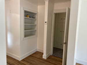 Hall with wood-type flooring and crown molding