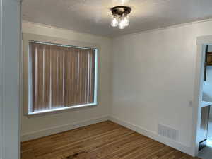 Spare room featuring wood-type flooring and a textured ceiling