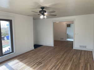 Empty room with dark hardwood / wood-style floors, ceiling fan, and a wealth of natural light