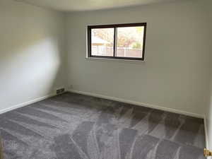 Empty room with carpet floors and a textured ceiling