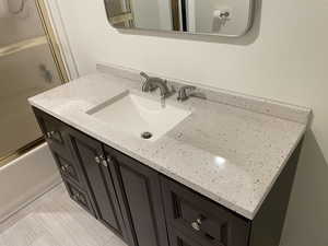 Bathroom featuring shower / bath combination with glass door and vanity