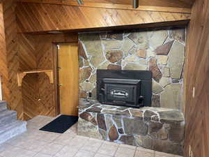 Room details featuring tile patterned floors, wooden walls, and beamed ceiling