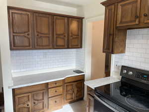 Kitchen with backsplash, electric range, and light stone countertops