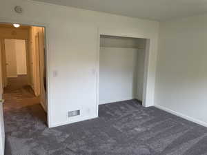 Unfurnished bedroom with dark carpet and a closet