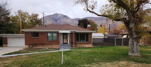 Ranch-style house featuring a mountain view, a garage, and a front lawn