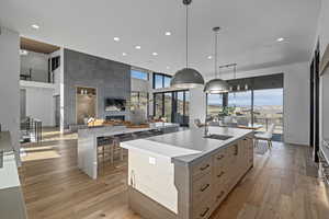 Kitchen featuring light brown cabinetry, a kitchen island with sink, sink, pendant lighting, and light hardwood / wood-style floors