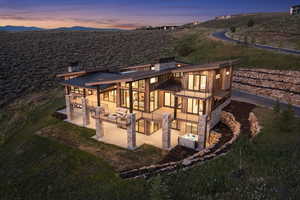 Back house at dusk featuring a mountain view, area for grilling, and a patio area