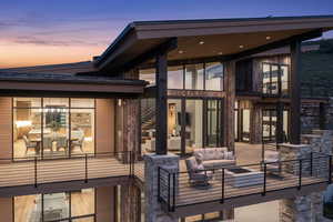 Back house at dusk with outdoor lounge area and a balcony