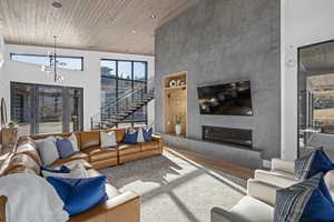 Living room with a chandelier, a fireplace, a towering ceiling, and wooden ceiling