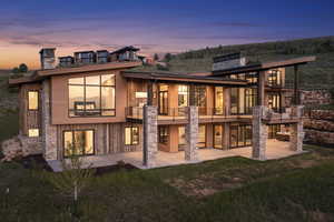 Back house at dusk with a patio and a balcony