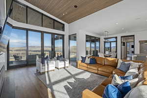 Living room featuring dark hardwood / wood-style floors, a healthy amount of sunlight, wood ceiling, and an inviting chandelier