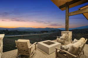 Patio terrace at dusk with a mountain view, a balcony, and an outdoor living space with a fire pit