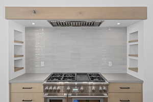 Kitchen featuring tasteful backsplash, light brown cabinetry, high end stainless steel range, and built in shelves