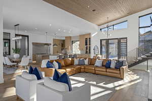 Living room with a chandelier, wooden ceiling, a high ceiling, and light hardwood / wood-style flooring