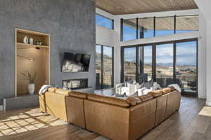 Living room with hardwood / wood-style floors, wood ceiling, a fireplace, and a towering ceiling