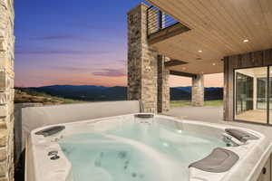 Pool at dusk featuring a mountain view and a hot tub