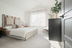 Bedroom with light colored carpet and vaulted ceiling