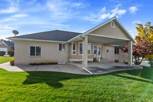 Back of house with a lawn and a patio