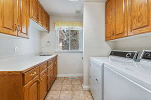 Laundry area featuring cabinets, light tile patterned floors, washer and clothes dryer, and sink