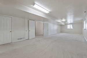 Basement with light carpet and a textured ceiling