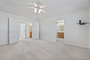 Unfurnished bedroom featuring ensuite bathroom, ceiling fan, and light carpet