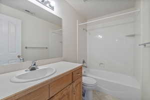 Full bathroom featuring vanity, tub / shower combination, a textured ceiling, and toilet