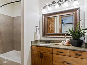 Bathroom featuring ceiling fan, vanity, and tiled shower / bath