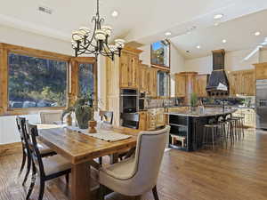 Dining area featuring dark hardwood / wood-style flooring, high vaulted ceiling, and an inviting chandelier