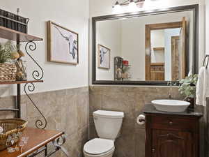 Bathroom featuring vanity, toilet, and tile walls