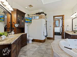 Bathroom featuring vanity, tiled bath, and tile patterned floors