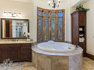 Bathroom featuring a chandelier, vanity, tiled bath, and tile patterned flooring