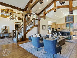 Living room featuring high vaulted ceiling, an inviting chandelier, sink, light hardwood / wood-style flooring, and beam ceiling